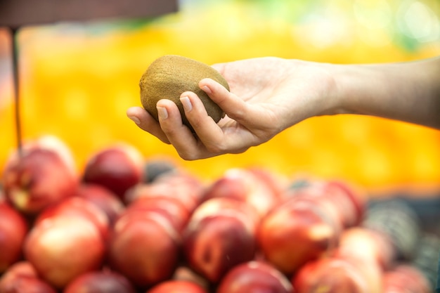 Vrouw hand kiezen kiwi in supermarkt.