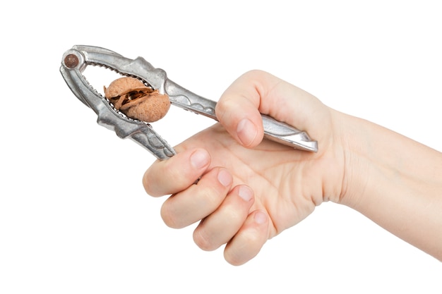 Vrouw hand kraakt een walnoot met metalen notenkraker geïsoleerd op witte achtergrond