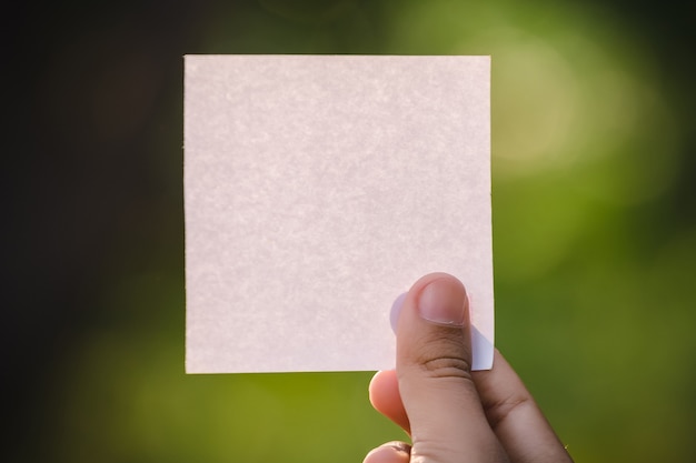 Vrouw hand met blanco papier op natuurruimte.