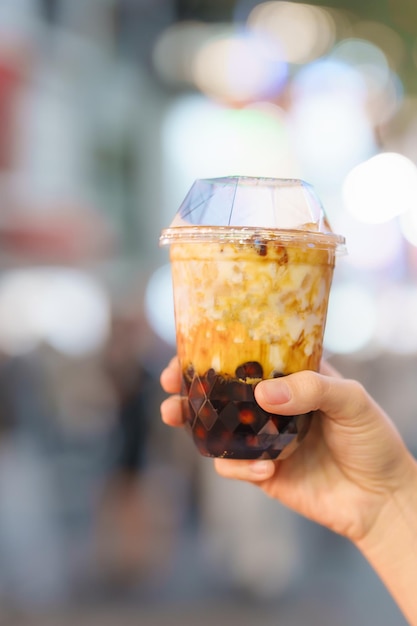 Vrouw hand met bruine suiker boba melkthee met tapiocaparels op de nachtmarkt beroemde taiwanese bubbelthee van taiwan street food en reizen in ximending taipei concept