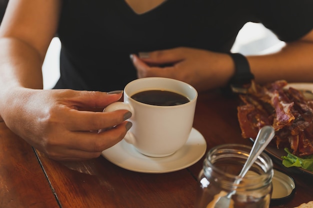 Vrouw hand met een kopje koffie op de houten tafel