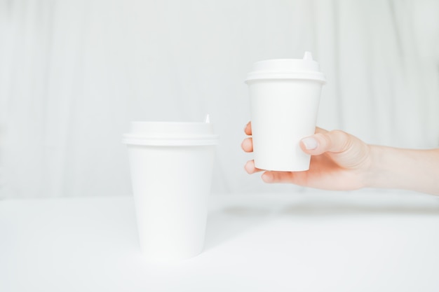 Vrouw hand met een papieren koffiekopje geïsoleerd op een witte achtergrond.