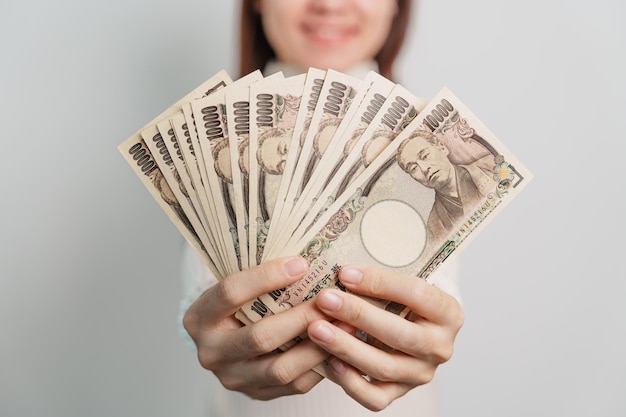 Vrouw hand met Japanse Yen bankbiljetten stapel Duizend Yen geld Japan contant geld Belasting Recessie Economie Inflatie Investeringen financiën en winkelen betalingsconcepten
