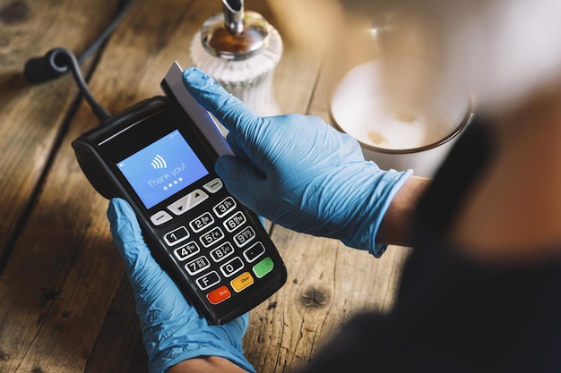 Vrouw hand met medische latex beschermende handschoenen veeg creditcard door terminal forpay in restaurant Bescherming voor Coronavirus COVID19