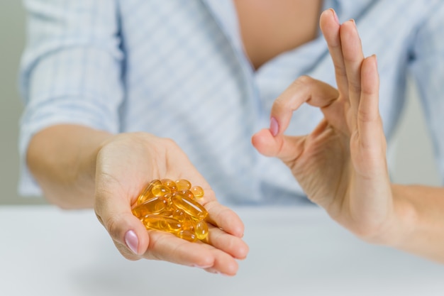 Vrouw hand met Omega 3 capsule en een teken ok