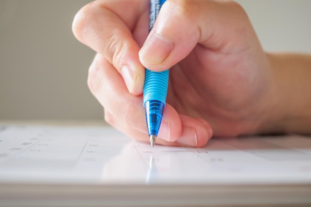 Vrouw hand met pen schrijven op kalender datum zakelijke planning afspraak vergadering concept