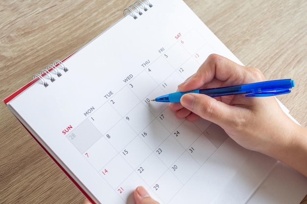 Vrouw hand met pen schrijven op kalender datum zakelijke planning afspraak vergadering concept