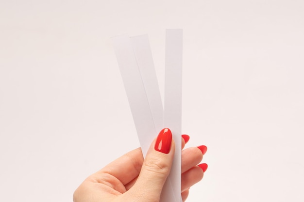 Vrouw hand met rode nagels met teststrips voor het parfum geïsoleerd op een witte achtergrond