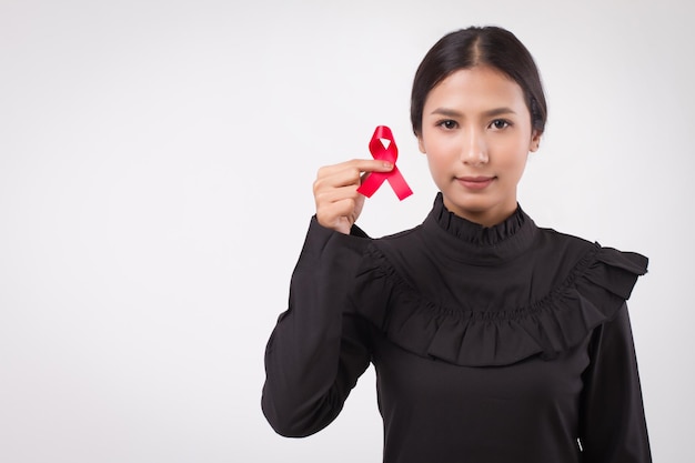 Vrouw hand met rood lint boog, hiv of aids bewustzijn symbool gepresenteerd door vrouw in studio opname. medisch, liefdadigheids-, fondsenwervingsconcept voor rood lint hiv aids day awareness