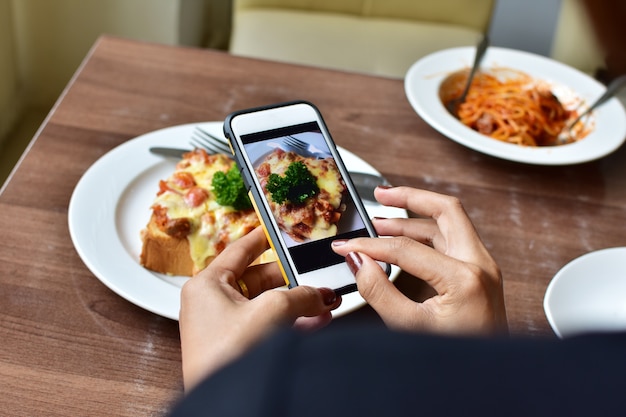 vrouw hand met slimme telefoon en foto eten op houten tafel