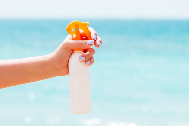 Vrouw hand met sunblock spray bij het strand