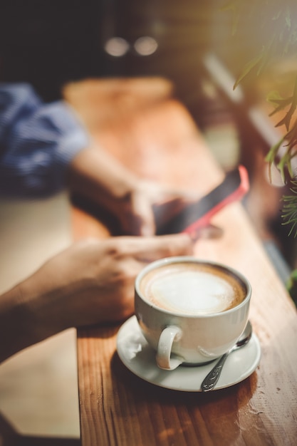 Foto vrouw hand nemen en het gebruik van mobiele telefoon en koffie drinken in de coffeeshop