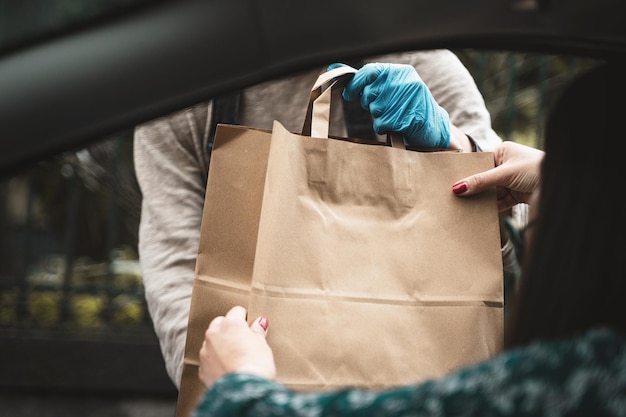 Vrouw hand ontvangen winkelen wenkbrauw papieren zak uit auto open raam rijden door pick-up van verkoper met blauwe handschoen uitzicht vanuit de auto in kamer voor tekst of copyspace