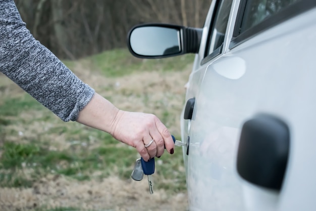 Vrouw hand opening auto deur met sleutel