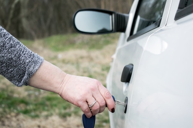 Vrouw hand opening auto deur met sleutel