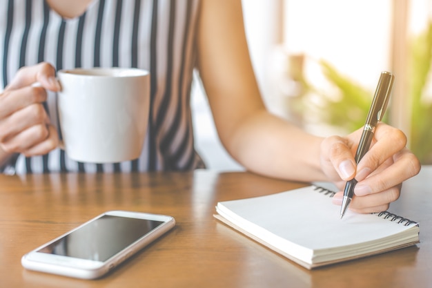 vrouw hand schrijft op een notitieblok met een pen.