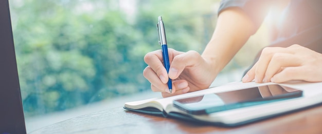 Vrouw hand schrijven op een notitieblok met een pen in de office.web banner.