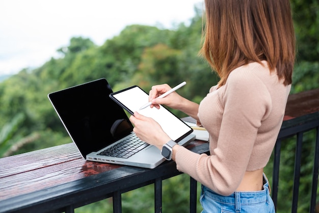 Vrouw hand schrijven op lege tablet met potlood op bureau met uitknippad laptopxA