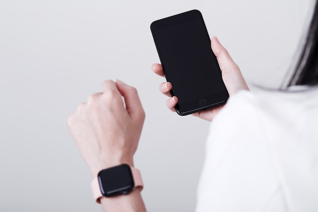 Vrouw hand slimme telefoon en slimme horloge