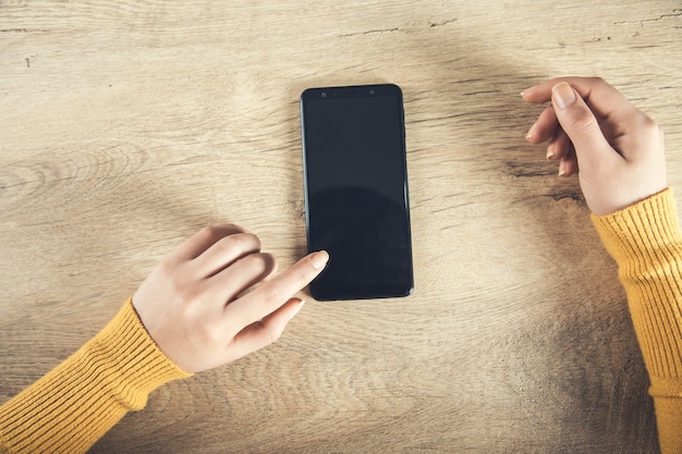 Vrouw hand slimme telefoon op de houten tafel