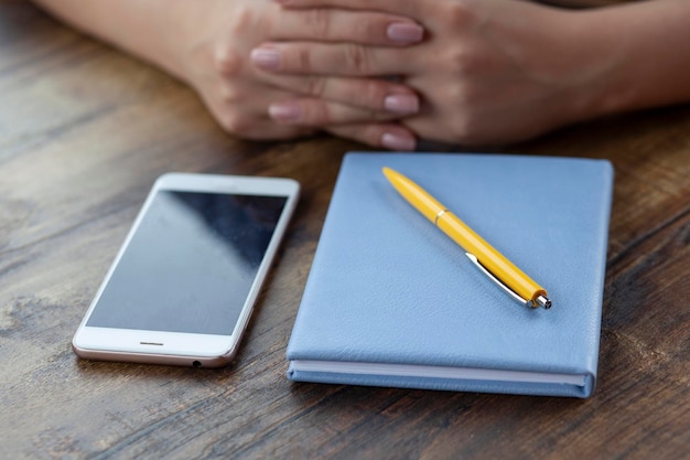 Vrouw hand telefoon en notitieblok