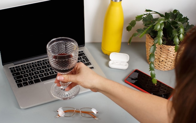 Vrouw hand toast met laptop met een glas rode wijn. Twee vrienden die thuis een videogesprek voeren op een laptop, close-up