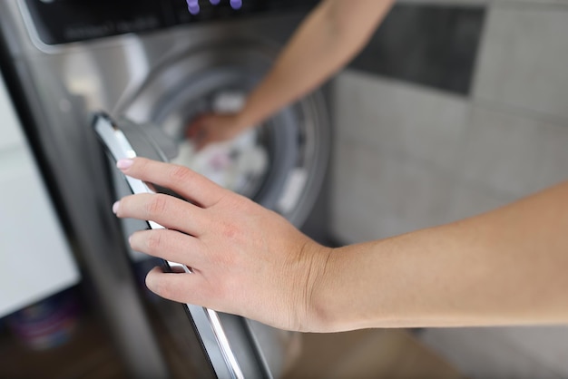 Vrouw hand vult trommel van wasmachine close-up