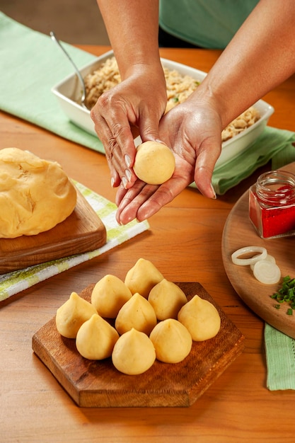 Vrouw handen bereiden Braziliaanse kroket coxinha de frango op een houten tafel