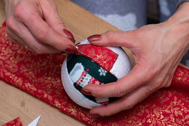 Vrouw handen close-up shot snijdt rode stof met een schaar, en het maken van decoraties.