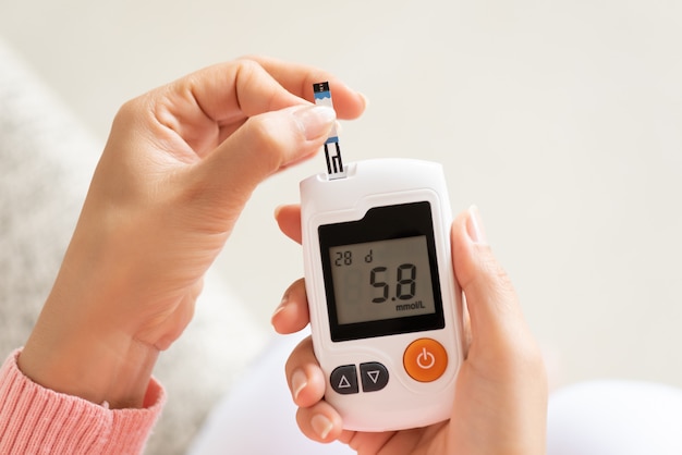 Vrouw handen controleren bloedsuikerspiegel door glucose meter voor diabetes tester