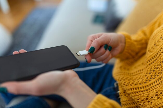 Vrouw handen die een oplader in een smartphone pluggen Vrouw die smartphone met powerbank laadvermogen gebruikt voor slimme telefoon Vrouw die batterij op mobiele telefoon thuis oplaadt