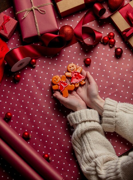 Vrouw handen houden peperkoek man cookie in de buurt van geschenken op inpakpapier