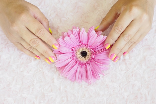 Foto vrouw handen in met een fel roze-geel kleurverloop manicure