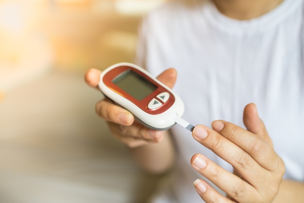 vrouw handen met behulp van glucosemeter op vinger om bloedsuikerspiegel te controleren