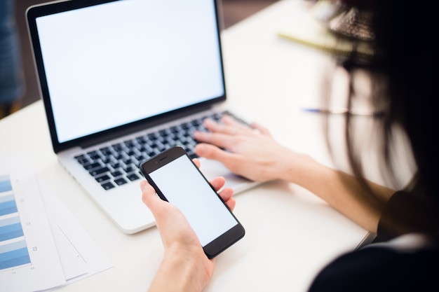 Vrouw handen met behulp van mobiele telefoon en laptop op kantoor