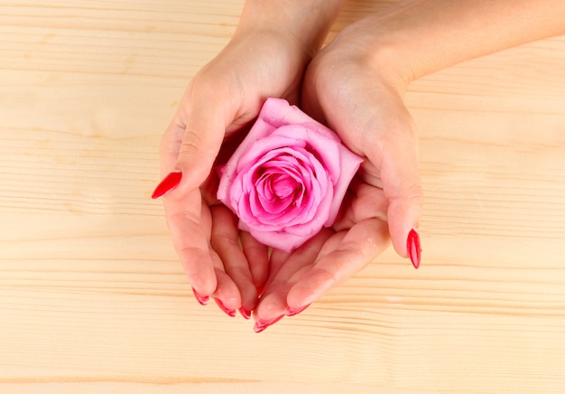 Vrouw handen met bloem op houten oppervlak