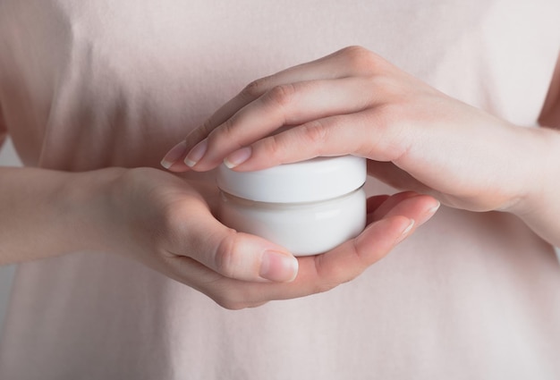 Vrouw handen met cosmetische crème in glazen pot