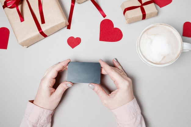 Vrouw handen met creditcard en laptop geschenkdoos met hart en koffie op witte achtergrond Valentine dag online winkelen concept vakantie achtergrond Bovenaanzicht