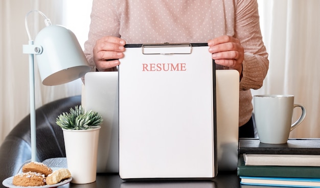 Vrouw handen met CV-applicatie in de buurt van haar werkplek met laptop.