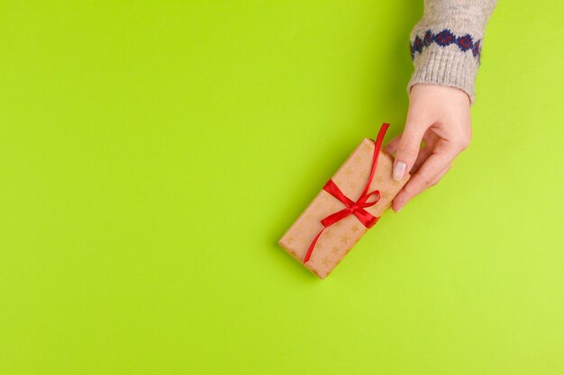 Vrouw handen met geschenkdoos op groene achtergrond