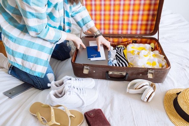Vrouw handen met horloge zetten kleren in koffer reizen concept kopie ruimte biometrisch paspoort laptop portemonnee