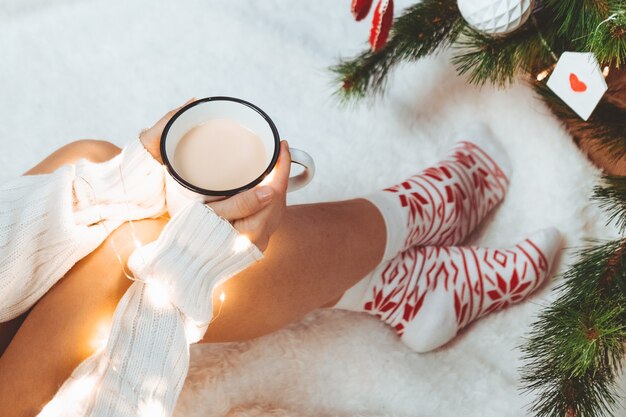 Vrouw handen met koffiemok in de buurt van kerstboom kopie ruimte