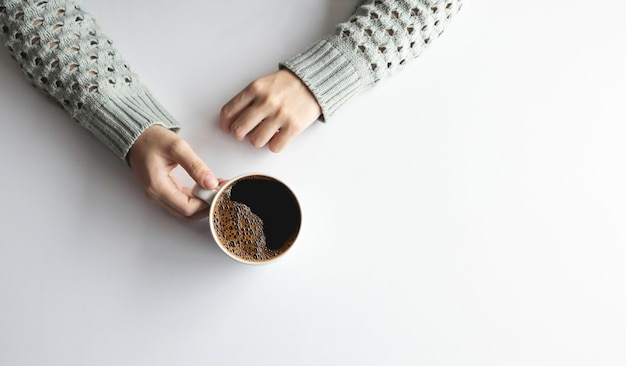 Vrouw handen met kopje koffie op witte tafel achtergrond bovenaanzicht