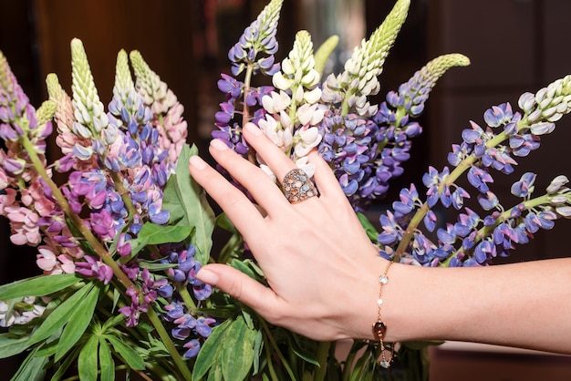 Vrouw handen met manicure en luxe sieraden ringen close-up van vrouwelijke hand op bloemen met mode...