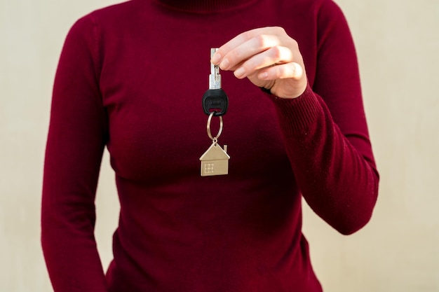 Foto vrouw handen met sleutel met sleutelhanger in de vorm van het huis