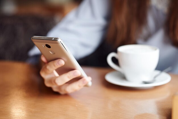 Vrouw handen met smartphone koptelefoon en kopje thee voor montage van de grafische weergave