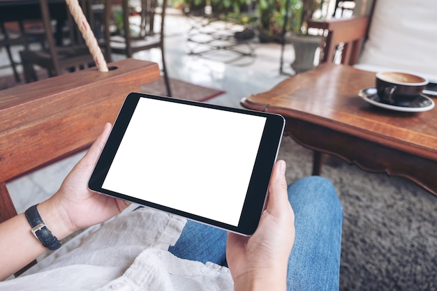 vrouw handen met zwarte tablet pc met leeg wit scherm horizontaal zittend in café