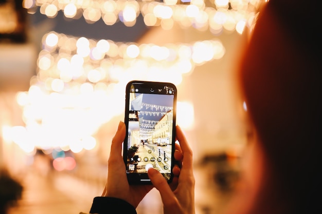 Vrouw handen nemen foto van nacht stadslichten met een smartphone