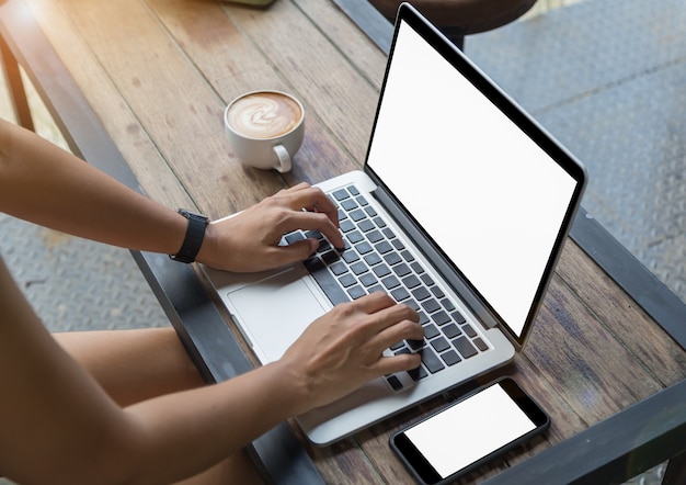 Foto vrouw handen op laptop met mobiele telefoon en koffie