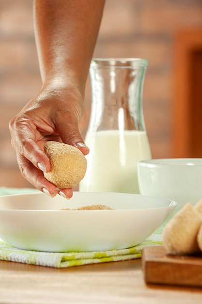 Vrouw handen paneren Braziliaanse kroket coxinha de frango met paneermeel op een houten keukentafel